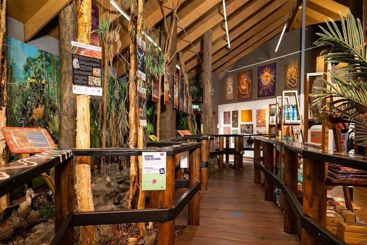 A rainy-season themed scene with people enjoying an indoor cultural venue, suggesting how to maintain routines even when outdoor light is limited.